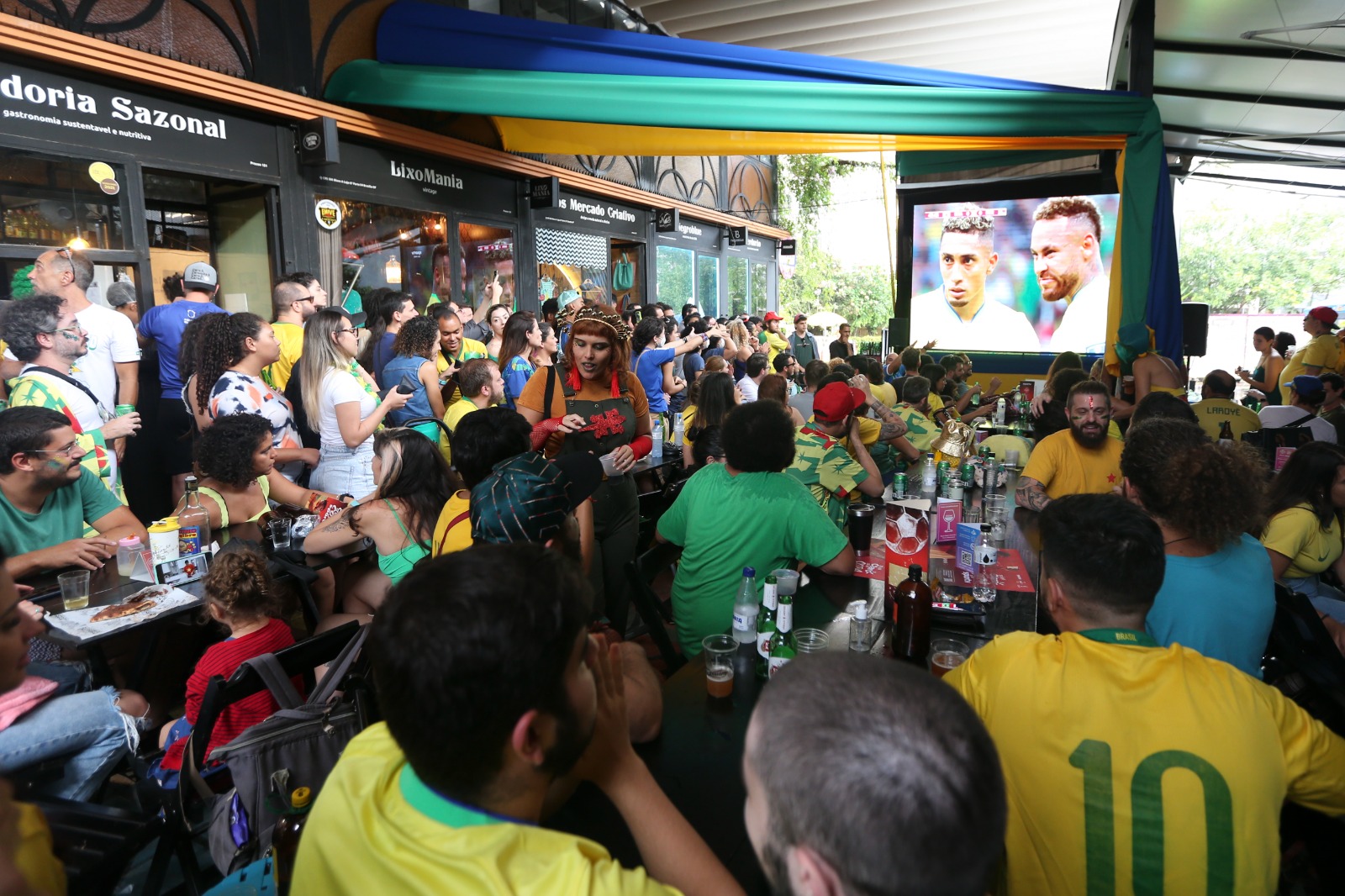 Torcedores de futebol com a camiseta do Brasil assistindo um jogo em um restaurante